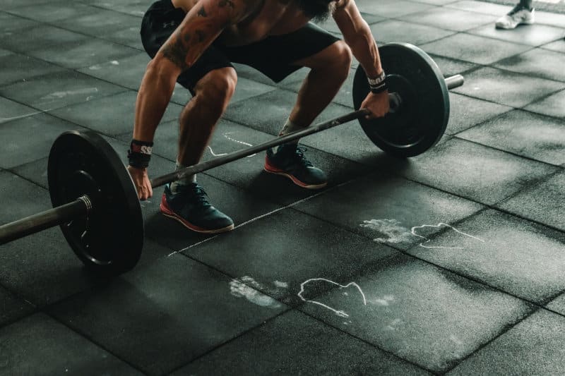 Bodybuilder der zu sehen ist, wie er ein Gewicht vom Boden aufhebt